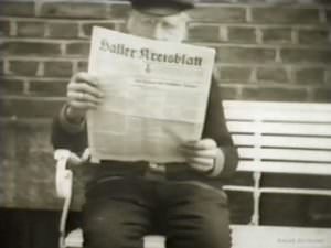 Alter Mann liest Zeitung vor seinem Bauernhof