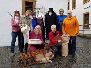 Eine Gruppe von sieben Frauen, die Museumsstücke aus den 1920er Jahren zeigen, darunter ein Charleston-Kleid.